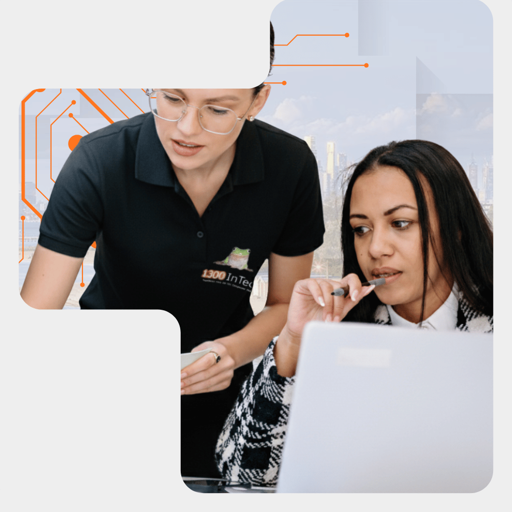 An 1300 INTECH member assisting a client with a laptop in an office on Blackburn