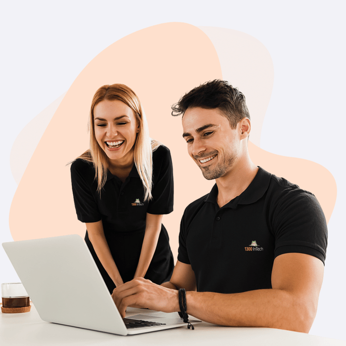 Two professionals smiling at a laptop after successfully completing a managed support project for a satisfied client