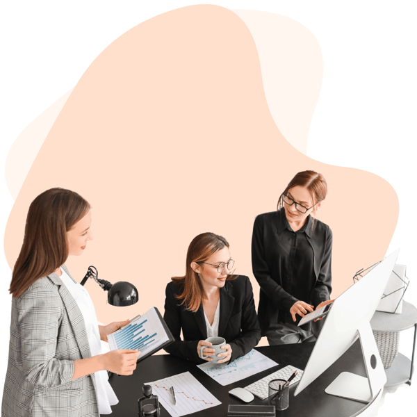 Three women collaborating on an IT support project for a small business, reviewing data and discussing strategies while working at a desk with a computer and documents.