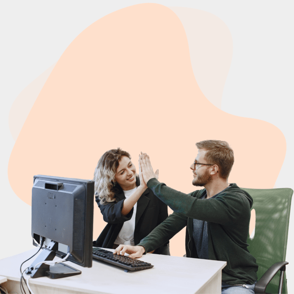 A woman and a man high-fiving in front of a computer, working together on an IT support project for a small business