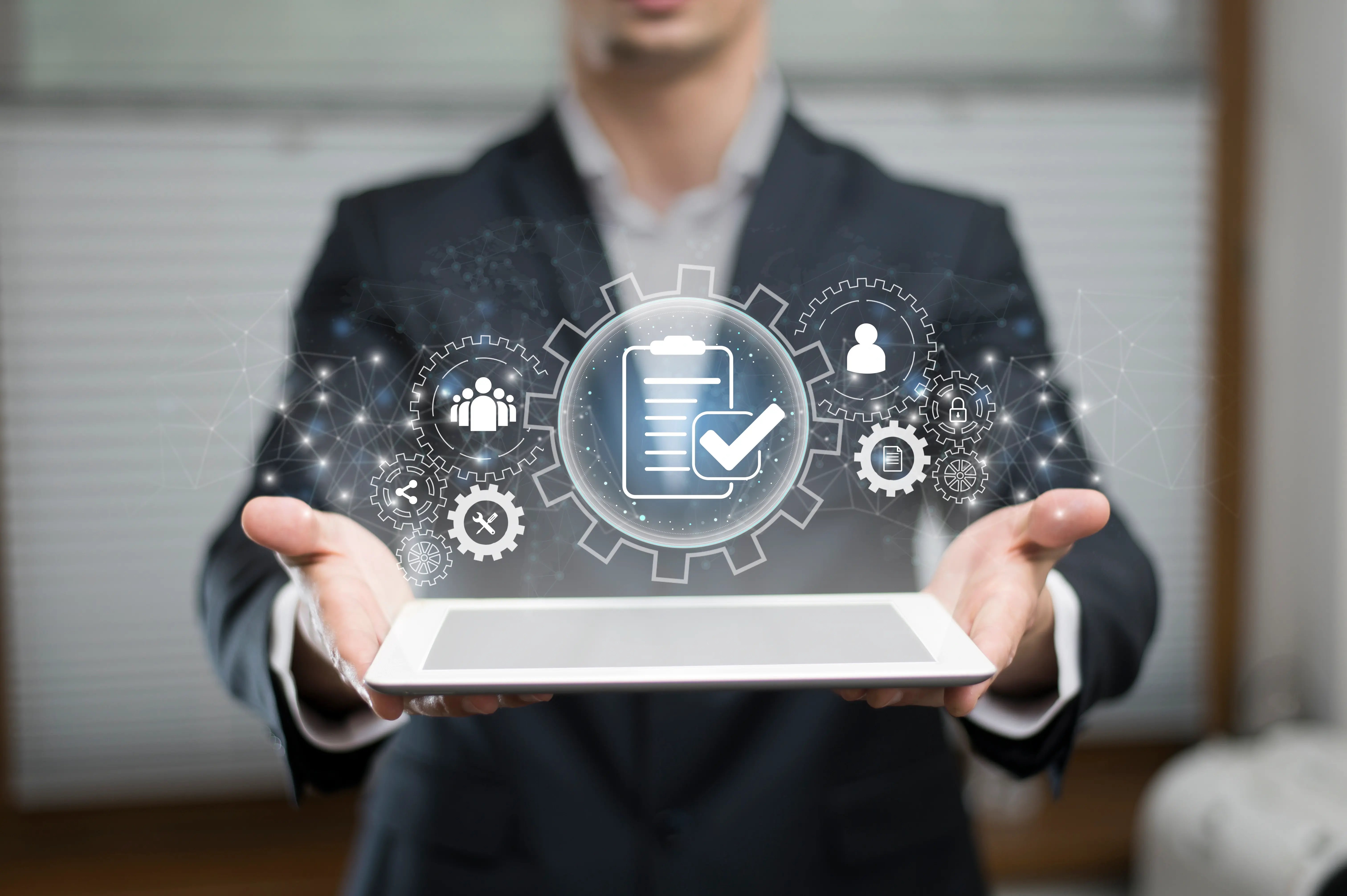 A business professional in a suit holds a digital tablet with floating technology icons above it, including gears, cloud storage, padlocks, and user symbols, representing managed IT services.