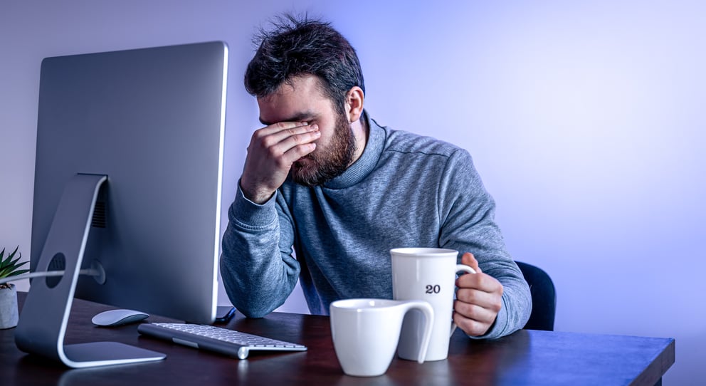 https://21106058.fs1.hubspotusercontent-na1.net/hubfs/21106058/tired-man-sits-front-computer-with-cup-coffee-colored-lighting.jpg